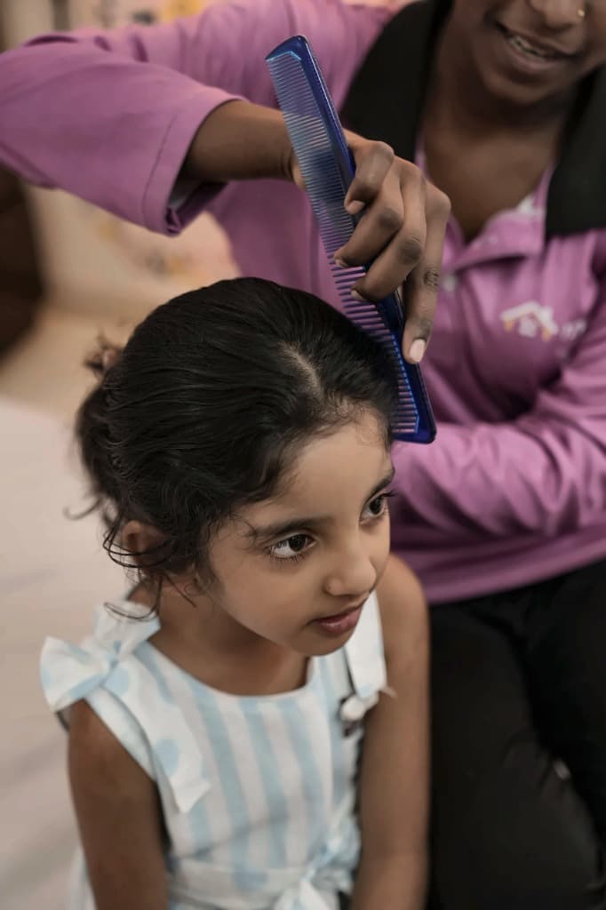 Nanny gently combing and grooming child