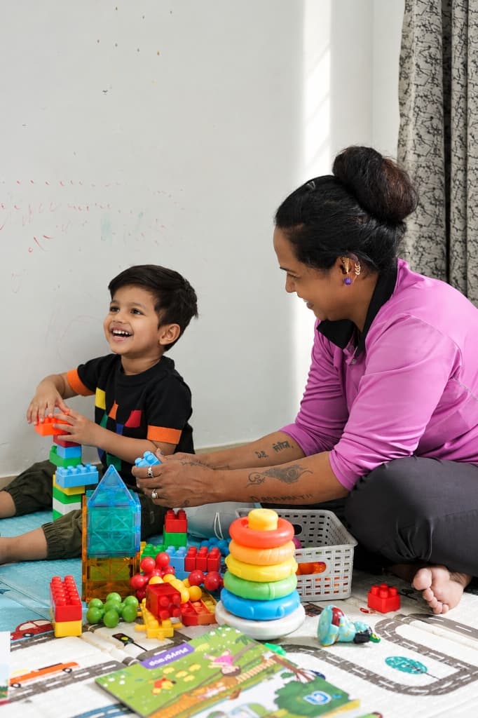 Nanny engaging and playing blocks with child at home